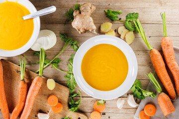 vegetable soup in bowl with ingredients on wooden board, top view