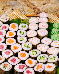 Sushi rolls arranged neatly on a wooden platter with fresh wasabi and ginger