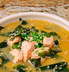 Delicious salmon soup with seaweed, sesame, and green onions in a bowl