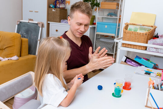 A young father and his daughter little child are sculpting together from plasticine in a room at home. - Powered by Adobe