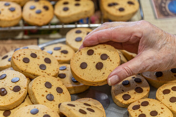 Hand picking chocolate chip cookie from fresh batch