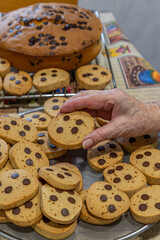 Hand picking fresh baked chocolate chip cookie from tray
