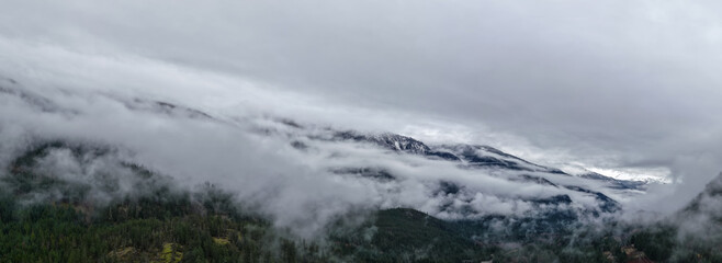 Misty Mountain Range in Clouds Over Forested Valley in British Columbia, Canada