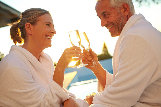 Love, sunset and people poolside with toast, bonding and anniversary celebration on holiday trip. Honeymoon, man and woman at resort with champagne cheers, connection and summer evening at lodge.