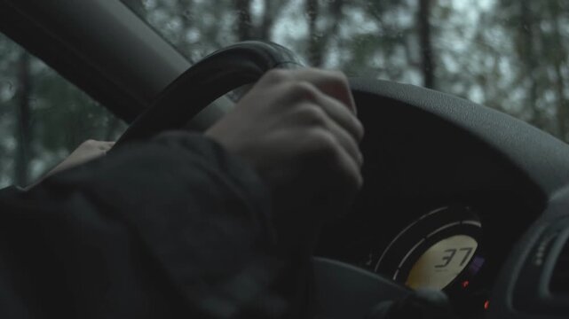 Cinematic close-up of a driver's hands gripping the wheel while navigating a rough, bumpy road. The camera shakes to show the off-road conditions as a forest passes by
