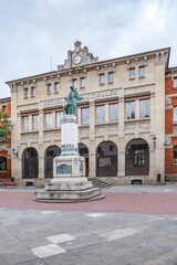 Historic Municipal Schools Building with Clock Tower and Monument Statue in Square in Pamplona
