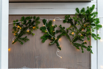 Christmas decoration with spruce branches and warm string lights at holiday market, natural winter ornaments creating cozy festive seasonal atmosphere