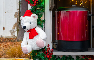 Christmas decoration with plush bear, red mulled wine container and festive garland at holiday market creating cozy winter seasonal atmosphere