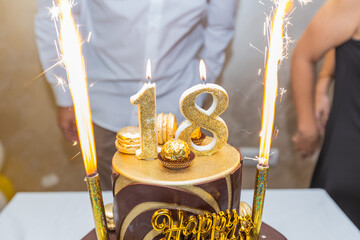 Luxurious 18th birthday cake adorned with gold candles, sparklers, and macarons