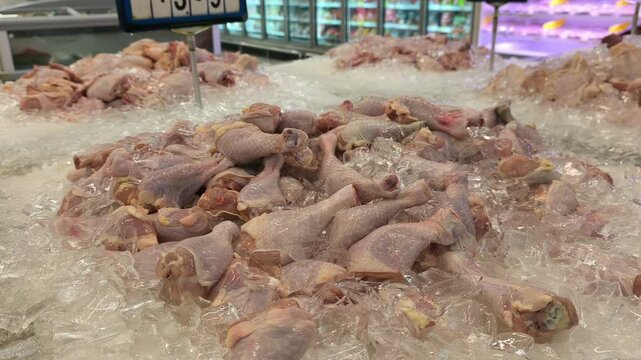 Cut chicken portions are separated and placed on ice for sale. These parts are displayed in the wet market section of a supermarket. Prices are determined by the weight and type of chicken piece.