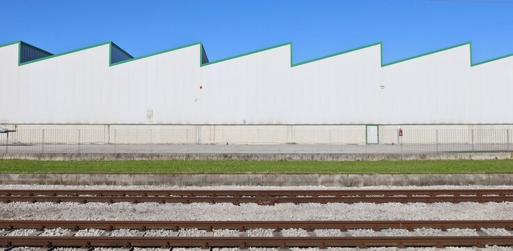 Large white industrial building with two railway tracks in front. Background for copy space.