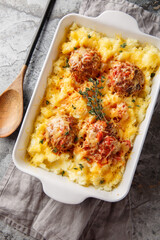 Meatball casserole with mashed potatoes, cheese, tomato sauce, and thyme in a baking dish on the...
