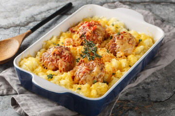 Hot mashed potatoes with Italian meatballs baked with cheese and herbs close-up in a baking dish on the table. Horizontal