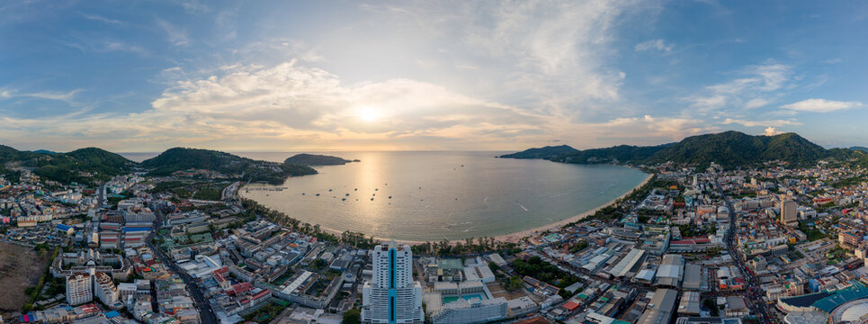 Panoramic sunset view over the bustling Patong Beach cityscape and bay in Phuket, Thailand.