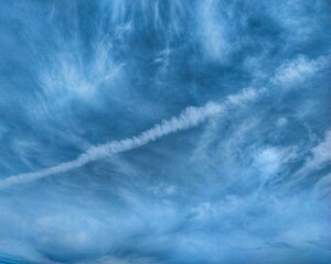 Bright blue sky with wispy clouds forming natural patterns, creating a peaceful and airy landscape suitable for nature backgrounds.