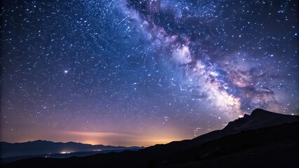 Stunning night sky view of the Milky Way stretching above silhouetted mountain peaks with stars and cosmic dust glowing brightly.
