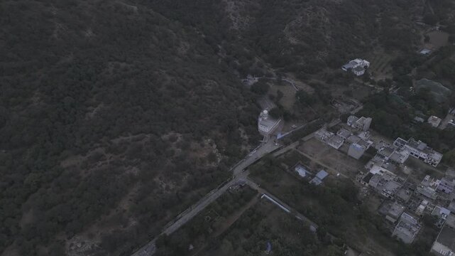 Aerial shot of Jamini Kund Road in Pushkar featuring a dramatic cloudy sky over the Aravali hills and the townscape below, capturing the calm evening atmosphere and the scenic landscape from above.