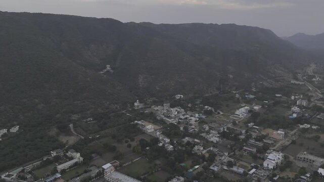 Aerial shot of Jamini Kund Road in Pushkar featuring a dramatic cloudy sky over the Aravali hills and the townscape below, capturing the calm evening atmosphere and the scenic landscape from above.