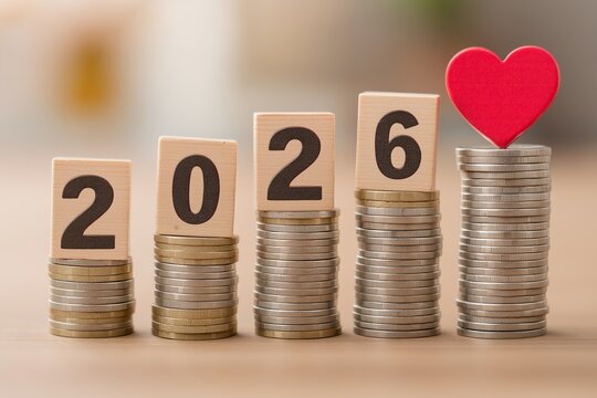 A stack of coins with wooden block numbers 2026 and a red heart on top representing a business money lifestyle or financial planning in the new year concept as a design template background.