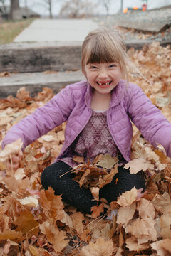 Young girl smiling playing in autumn leaves