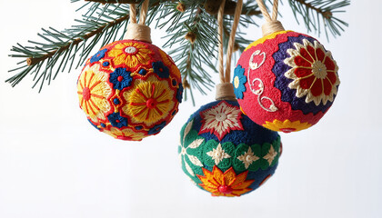 Handcrafted decorative Christmas ornaments hanging from a pine branch on a white background