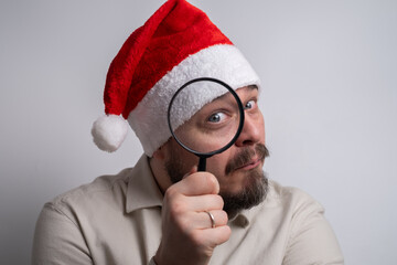 Man in santa hat looking through magnifying glass