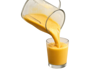 Pouring fresh yellow fruit smoothie from a blender pitcher into a glass, preparing a healthy liquid drink