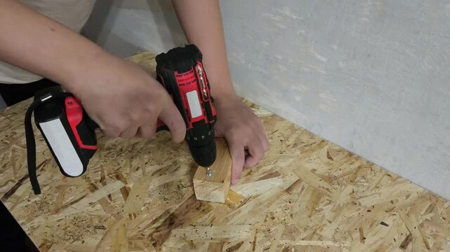 A man drives screws with a power drill into an OSB board. Concept of furniture assembly, renovation