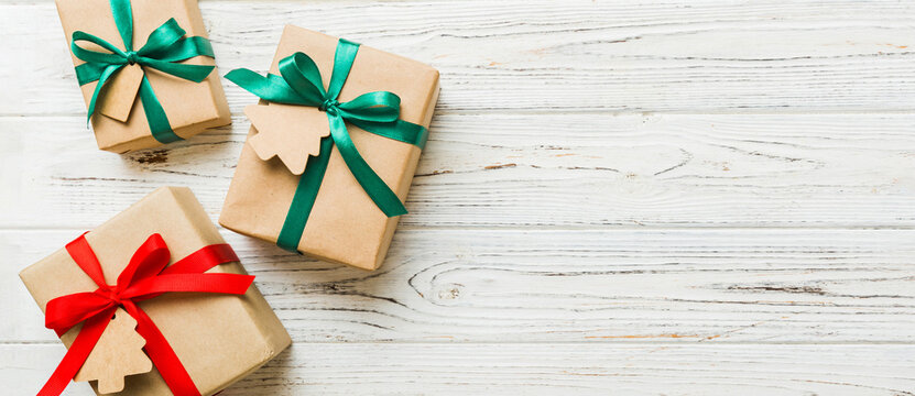 wrapped christmas or other holiday handmade present in paper with colored ribbon. Present box, decoration of gift on colourfull table, top view with copy space