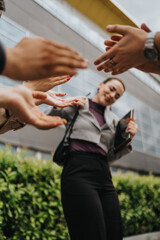 Obraz premium A group of business professionals engaging in team bonding through high-fives in an outdoor setting.