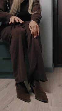 Woman sitting farther away, similar to previous close-up. A woman sits quietly in a dim room, looking thoughtful and distant, creating a calm yet introspective morning atmosphere.