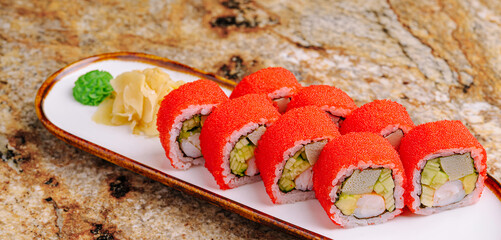 Colorful sushi rolls served on a plate with wasabi and ginger