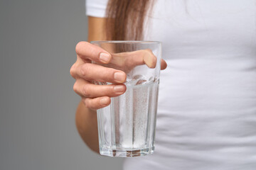 Close-up of woman holding glass of water with dissolving vitamin tablets 
