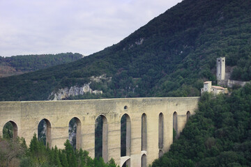 Fototapeta premium Arched bridge and aqueduct known as the Ponte delle Torri and the Fortilizio dei Mulini fortress. Spoleto, Umbria Region, Italy.