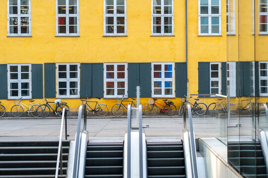 Modern architecture with a bright facade in yellow, repeating windows, and dynamic stairs creating urban pattern accents in copenhagen denmark