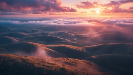 Aerial view of rolling green hills at sunset with soft natural lighting illuminated clouds reflecting warm orange pink and purple hues showcasing the tranquility of the landscape and gentle mist - Powered by Adobe