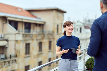Friendly Office Conversation On Rooftop Balcony Between Colleagues With Coffee Mug