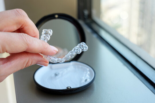 Closeup of a hand holding a clear dental aligner with the case softly blurred in the background, highlighting the transparent structure and clean details of modern orthodontic tools