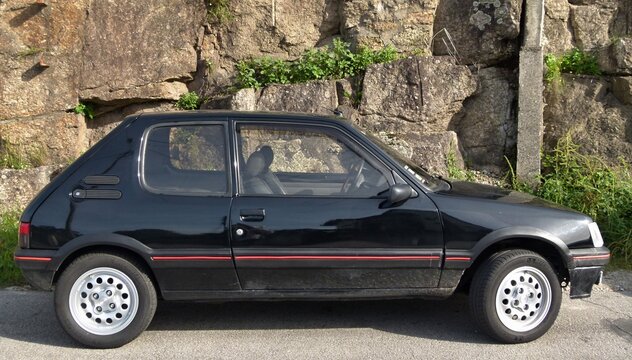 Black Peugeot 205 GTI hot hatch parked against rock