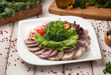 Traditional Kazakh meat platter featuring sliced kazy zhaya onions fresh herbs and lettuce garnish
