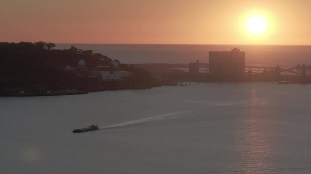 Boat passing up the Tagus river in Lisbon, Portugal, by grain silo plant. Winter aerial drone shot at sunset