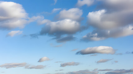 A picturesque view of a serene blue sky adorned with fluffy white and grey clouds in daylight hours