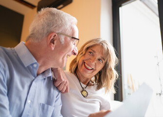 Obraz premium Happy senior couple smiling and looking at each other, enjoying a relaxed moment at home