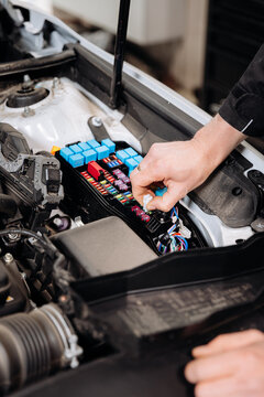 Mechanic replacing car fuse in engine bay fuse box, auto service maintenance close up