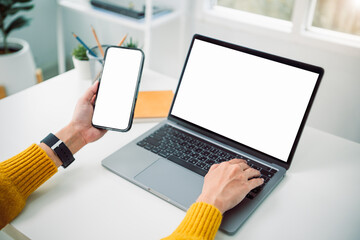 Asian business woman using mockup smartphone and laptop at home office concept of digital multitasking remote communication technology synchronization and modern online business productivity