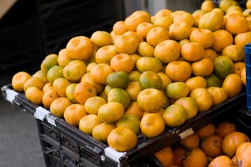 Ripe mandarins stacked at an outdoor market stand, showcasing vibrant color and natural texture for food, farming, and retail concepts.