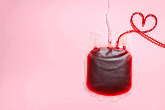 Blood donation bag filled with red liquid on a pink background