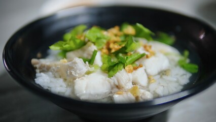 Rice porridge with fish and vegetable in black bowl,Thai style food