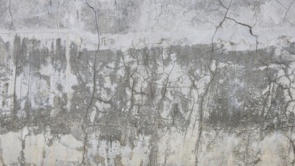 The old grey cement wall is stained, peeling and has a rough texture. The wall has cracks and scratches from time. The wall of an ancient building. Texture and background image.