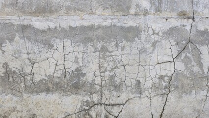 The old grey cement wall is stained, peeling and has a rough texture. The wall has cracks and scratches from time. The wall of an ancient building. Texture and background image.